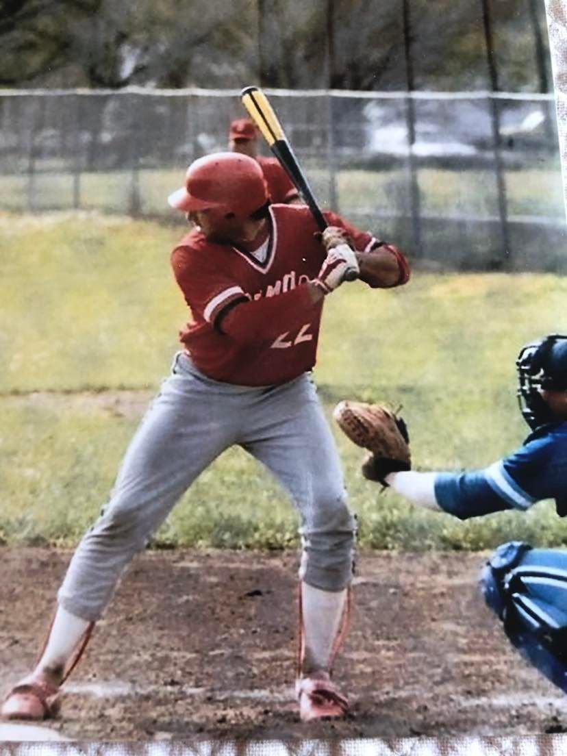 Brian Moon at bat in a red uniform, bat raised, catcher set behind him